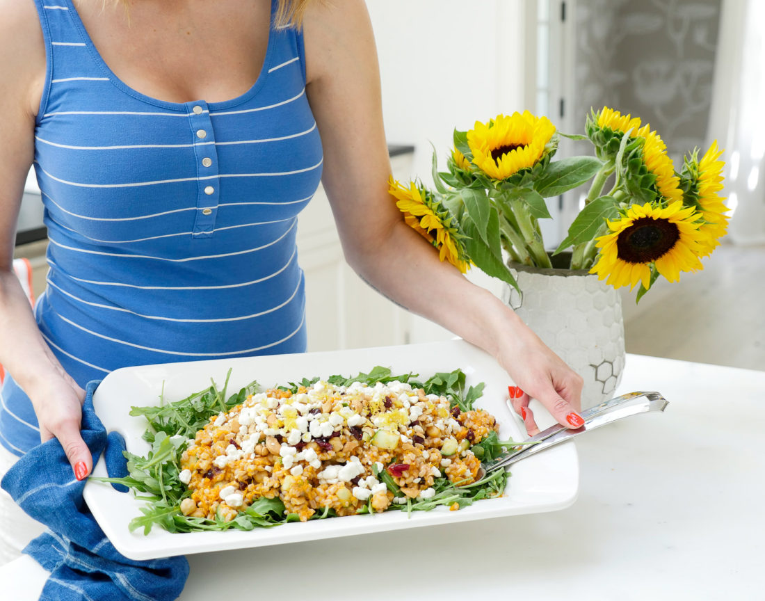 Happily Brenda After Autumn Farro Salad with Sweet Potato, Cucumber, Chickpeas, cranberries, goat cheese, cashews, arugula, and lemon zest phtographed in a marble kitchen with a blue shibori dyed tea towel and sunflowers