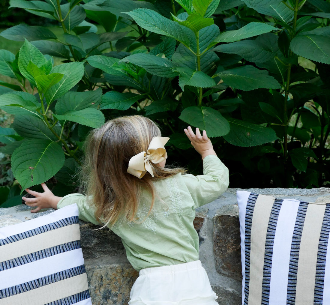 Photo of Marlowe Martino on Happily Brenda After blog wearing a green tunic and white ruffled shorts with a beige bow in her hair