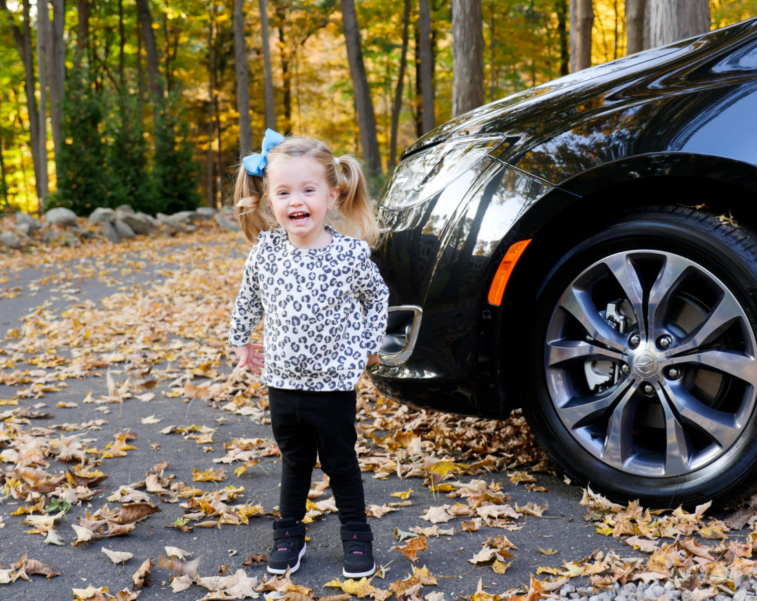 Marlowe Martino pictured wearing a leopard print sweatshirt and black leggings, surrounded by Autumn leaves
