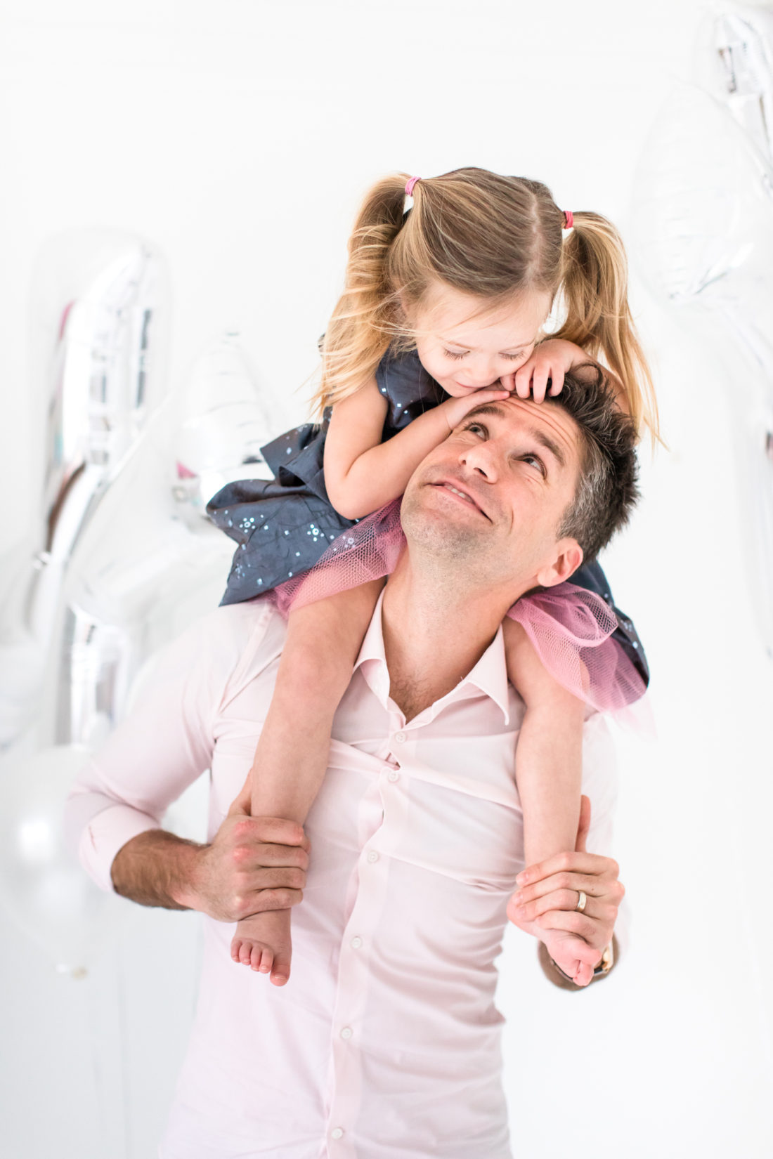 Marlowe Martino sits on her daddy's shoulders wearing a blue and pink sparkly dress