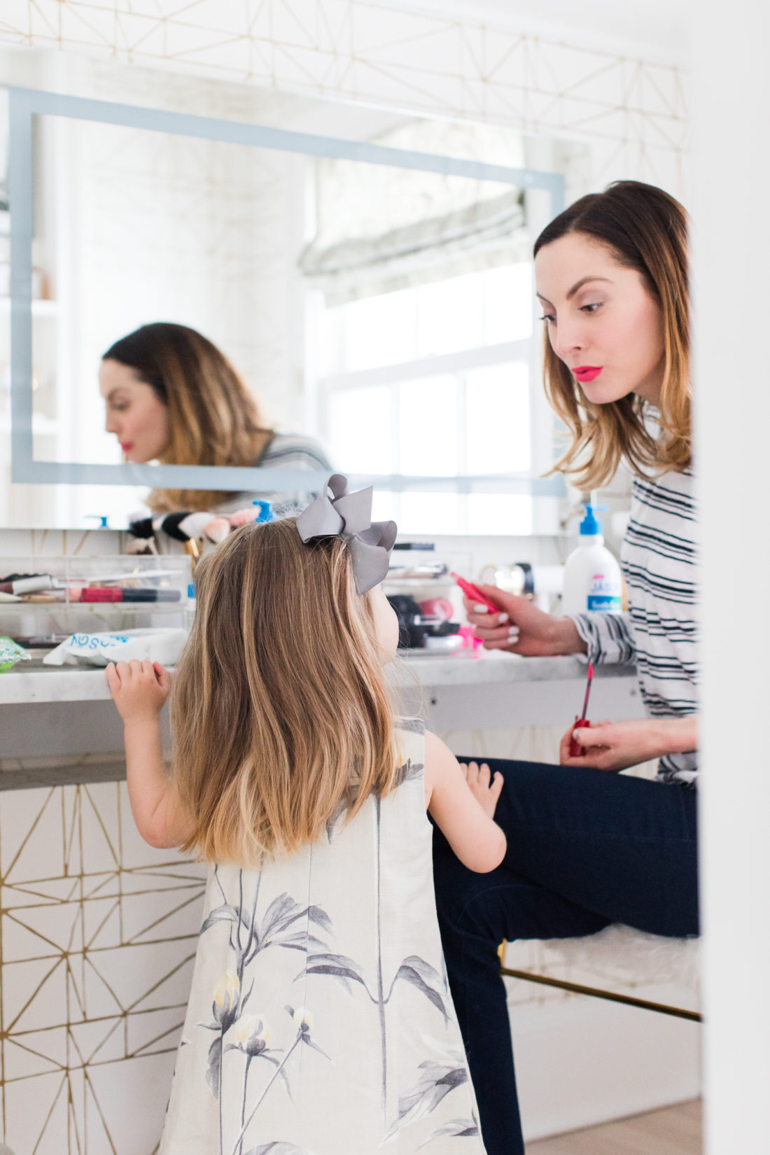 Brenda Mierish martino applies makeup in her Glam Room while two year old daughter Marlowe looks on