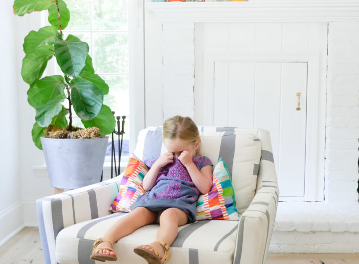 Marlowe Martino wears an embroidered dress and sits in a striped armchair in the family room of her Connecticut home