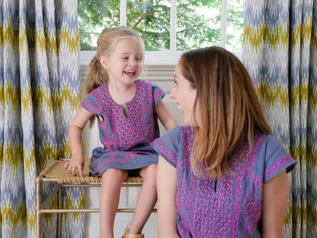 Brenda Mierish Martino and Marlowe Martino wear matching embroidered dresses and sit together in the living room of their Connecticut home