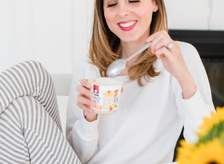 Brenda Mierish Martino sits at the kitchen table in a pair of grey and white striped pajamas and eat breakfast next to a vase of sunflowers