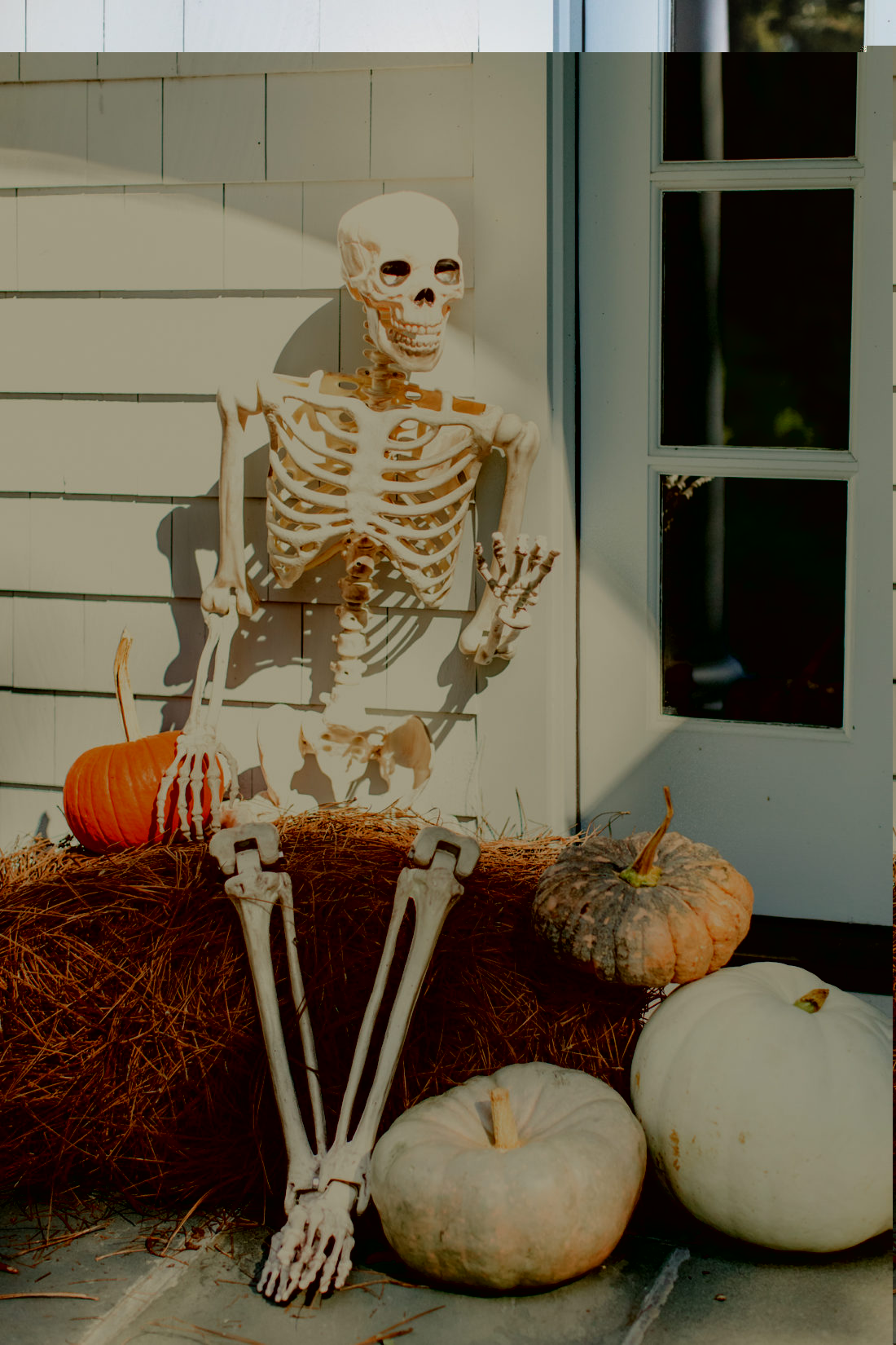 A skeleton sits on a bale of pine needles, surrounded by pumpkins in the spooky entryway of Brenda Mierish Martino's Connecticut home