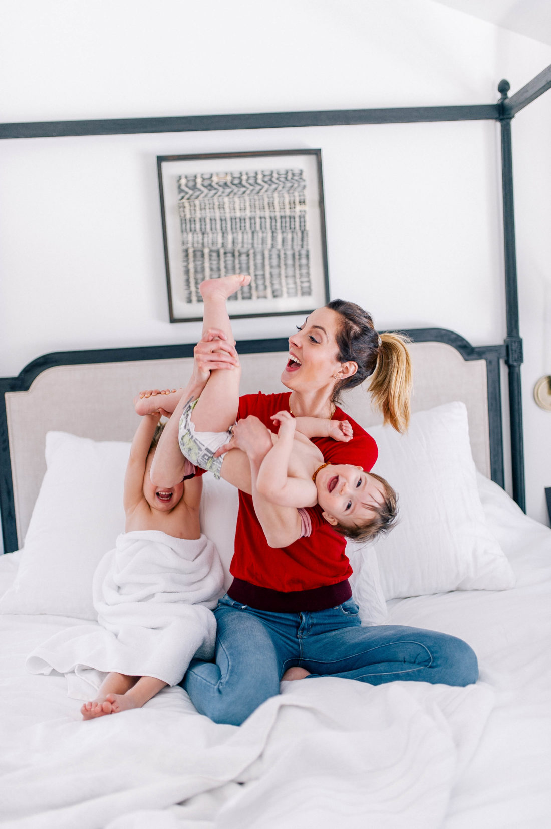 Brenda Mierish Martino wears a red sweater and jeans, and lifts one year old son, Major, in the air to tickle him